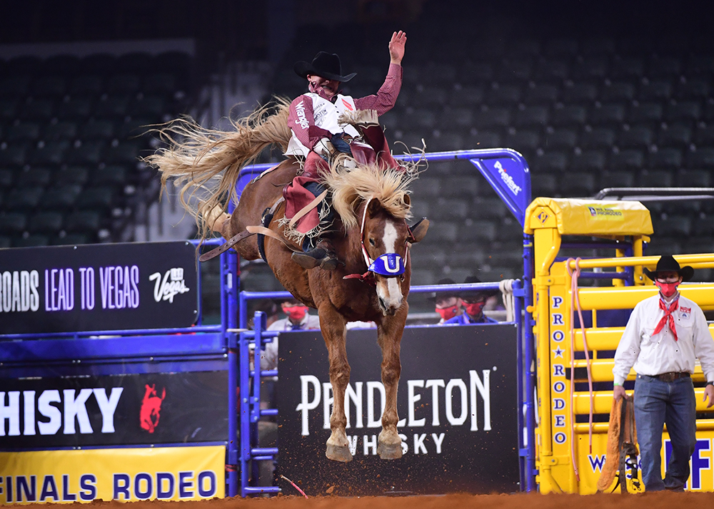 Clayton Biglow rides Flying U Rodeo's Lil Red Hawk for 85 points to finish in the money during the first round of the National Finals Rodeo in Arlington, Texas. (PHOTO BY JAMES PHIFER)