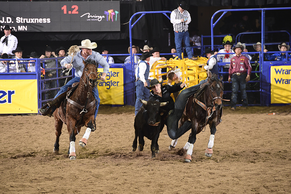 J.D. Struxness squeezes himself between his horse and his steer en route to a 3.9-second run Sunday to place fourth in the fourth round. (PRCA PRORODEO PHOTO BY JAMES PHIFER)