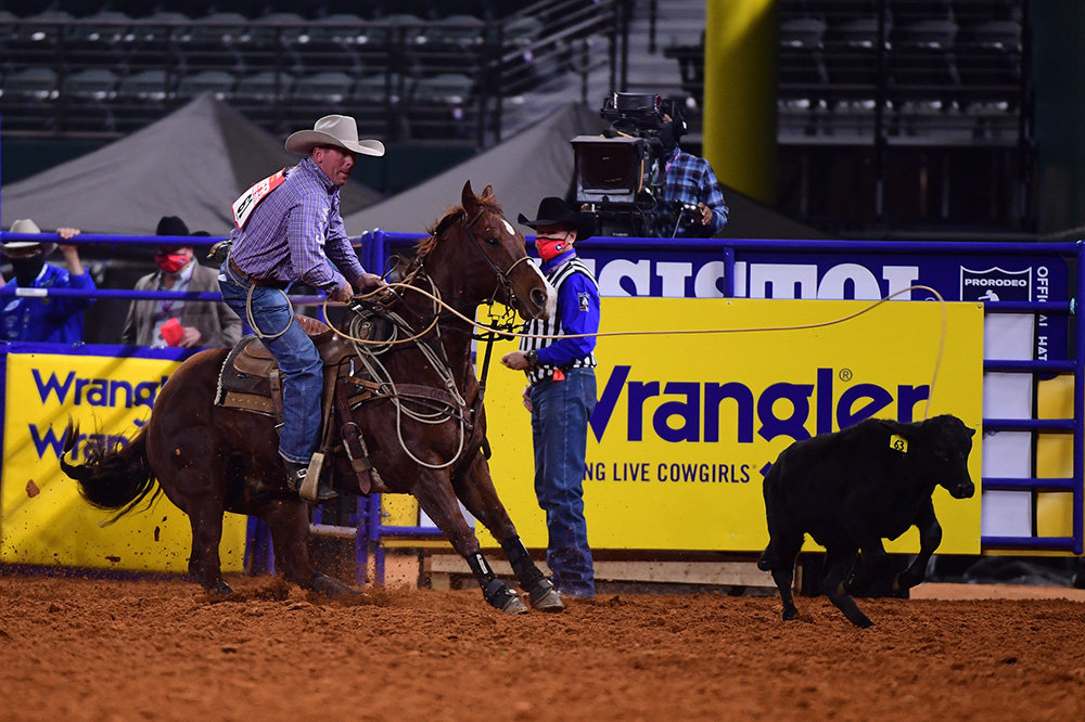 Ryan Jarrett dismounts his horse en route to a 7.8-second tie-down roping run to finish third in Thursday's eighth round of the National Finals Rodeo. (PHOTO BY JAMES PHIFER)